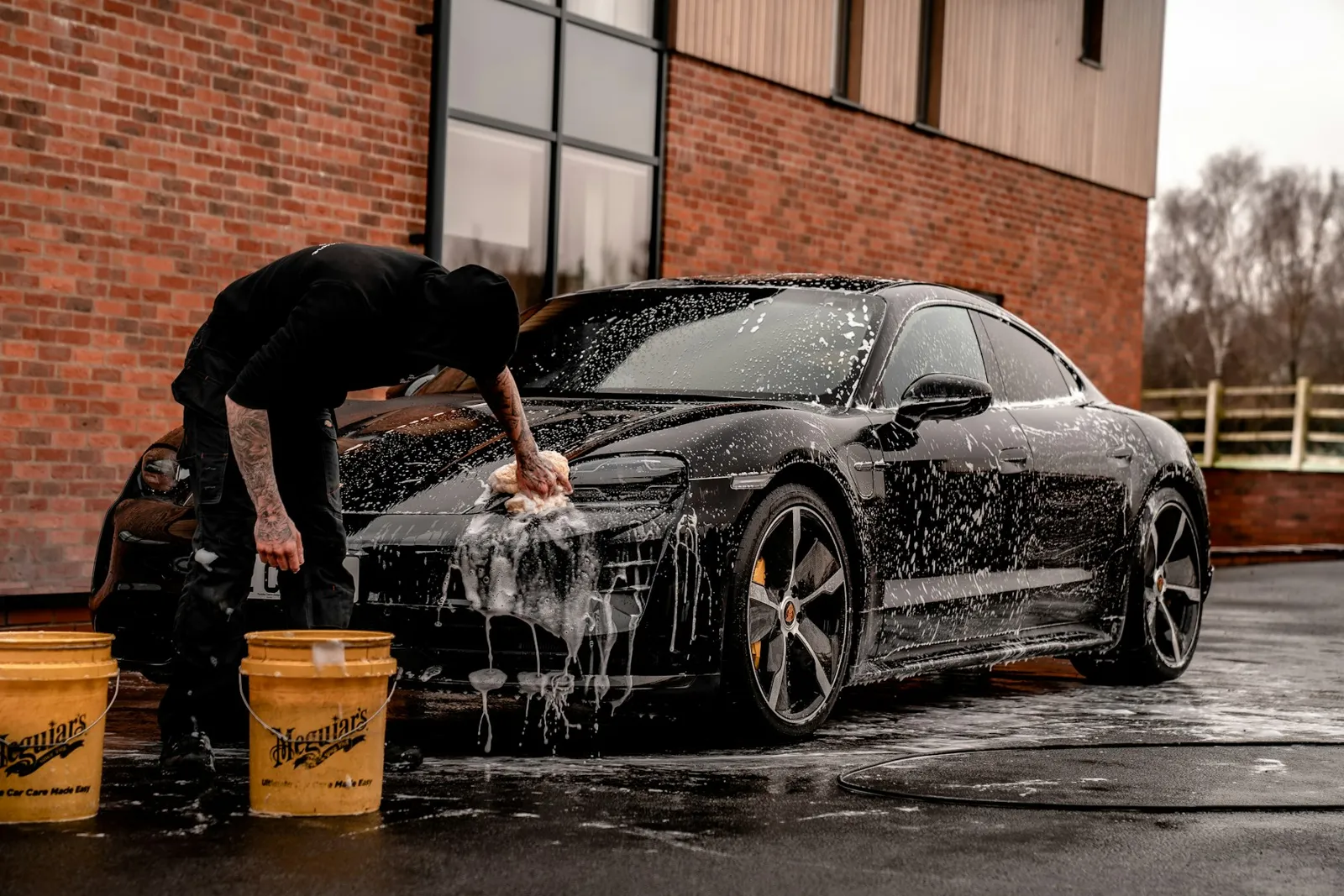 Hand washing a black car with the two-bucket method